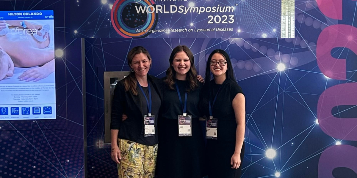 Three recipients of the ThinkGenetic Foundation Pro-GC program standing together in front of a banner for the 2023 WORLD Symposium